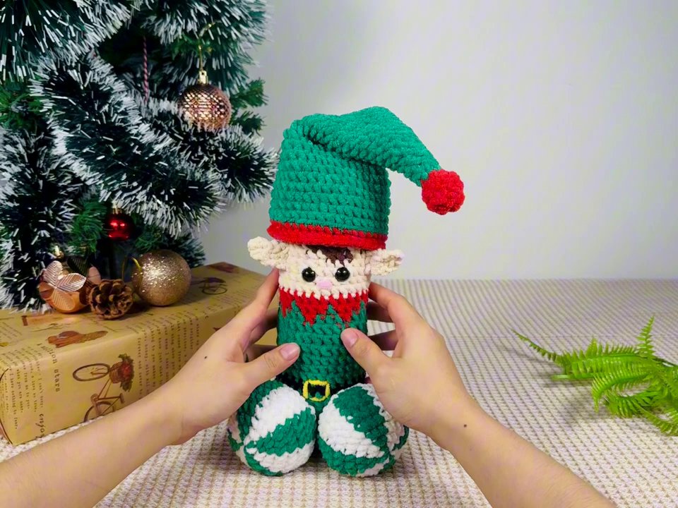The Enchanting World of Handmade Crochet Elf Dolls: A Festive Showcase 3 The hands adjust their grip, bringing the doll slightly closer to offer a more direct view of its facial features and costume texture.