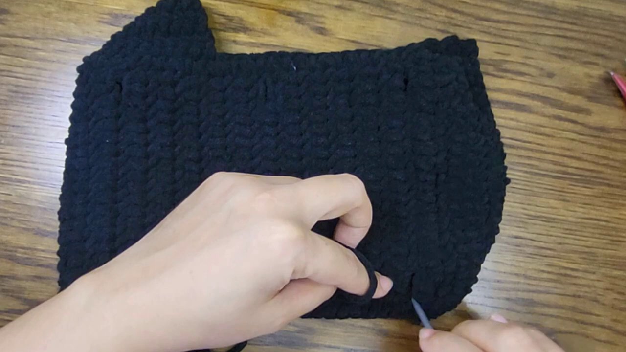 Crafting Comfort: A Step-by-Step Guide to Crocheting Your Own Bicycle Seat Post Cover 3 The hands begin the initial stitches, looping the black yarn with the blue hook.