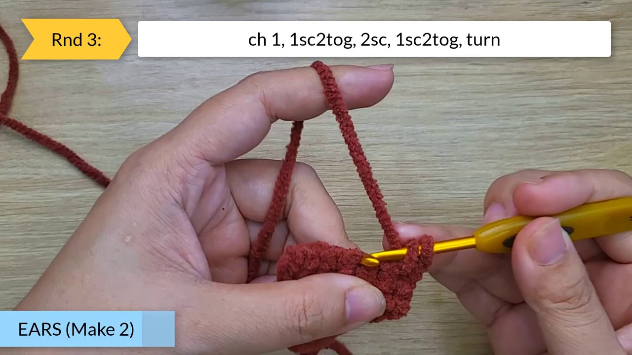 Craft Your Own Adorable Crochet Dog Bun: A Beginner's Step-by-Step Guide 7 An overview shot showing the crochet workspace with balls of pink, red, and white yarn in the corner, emphasizing the materials used.